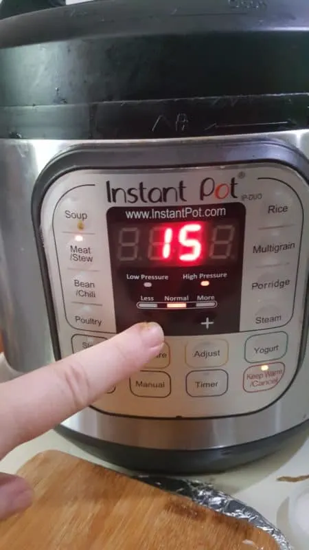A hand setting the Instant Pot to 15 minutes on the Meat/Stew setting for cooking Arroz con Pollo