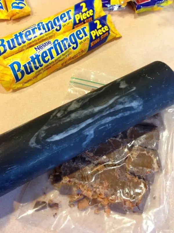 butterfinger cookie bars crusing butterfingers with rolling pin