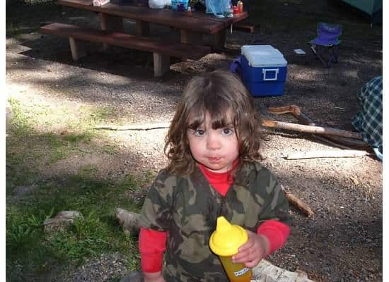 little girl camping with sippy cup of water