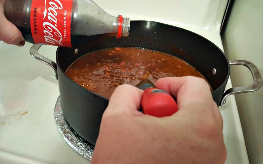 coca cola chili recipe stirring in the tomato sauce