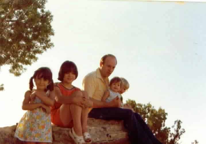 fathers and daughters sitting on rock