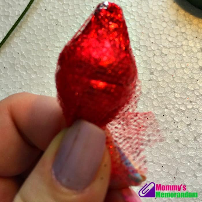 Close-up of wrapping red Hershey Kisses in glitter tulle to create a Hershey Kisses rose.