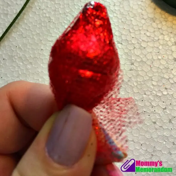 Close-up of wrapping red Hershey Kisses in glitter tulle to create a Hershey Kisses rose.