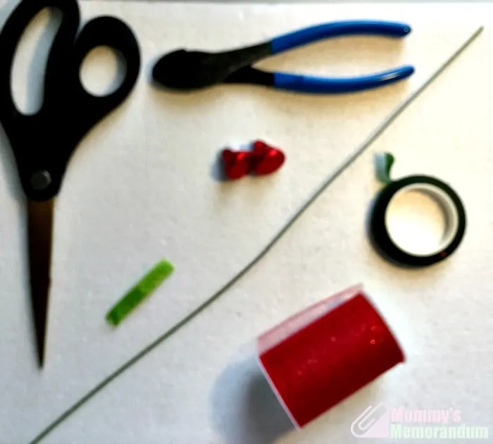 Supplies needed to make Hershey Kisses roses, including scissors, wire, tape, and red glitter tulle.