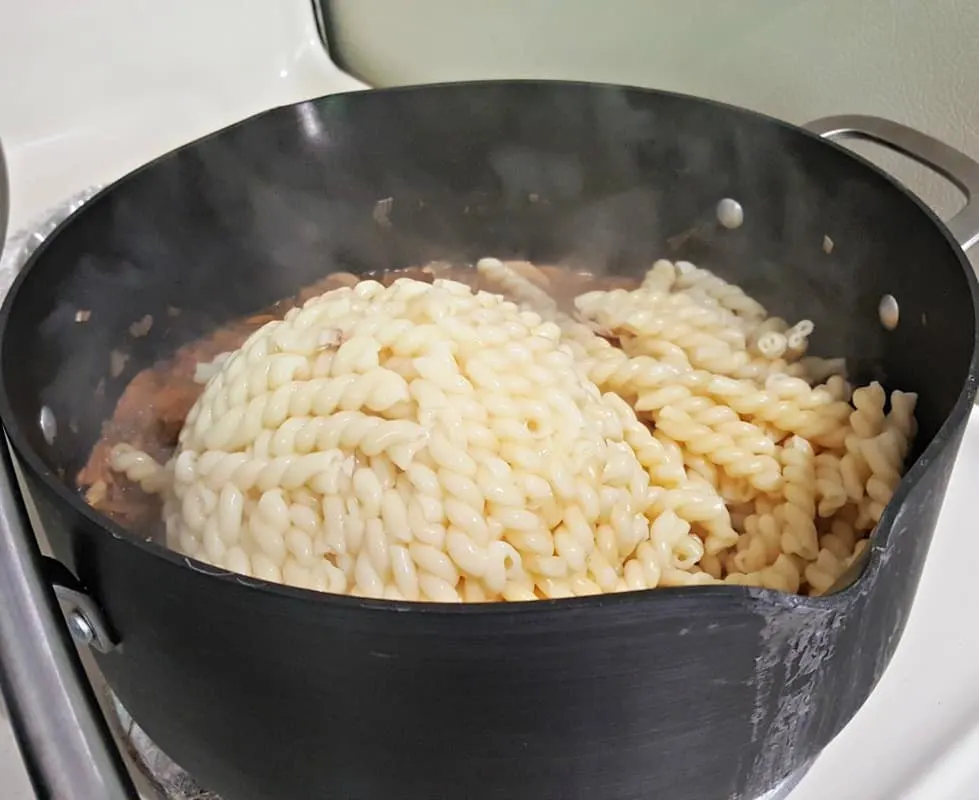 home chef adding cork screw pasta