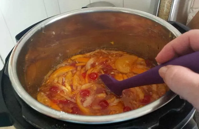 Stirring sugar into marmalade mixture to dissolve and prepare for boiling