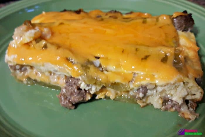 A slice of green chile quiche displaying layers of chiles, sausage, and cheese on a plate, ready to eat.