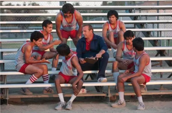 McFarland actors seated on a bench with Kevin Costner during a scene from McFarland, USA.