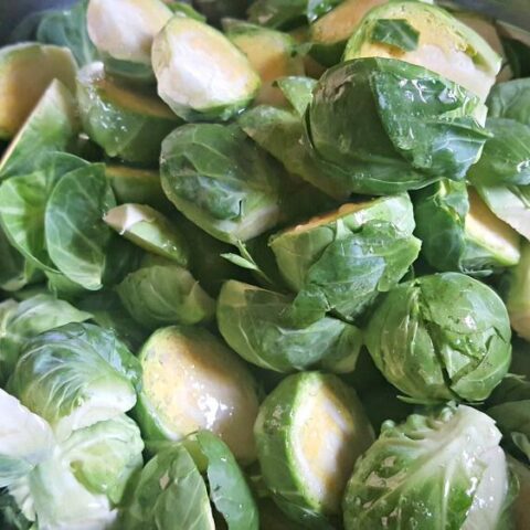 Halved Brussels sprouts drizzled with melted butter, prepared for roasting to a crispy texture