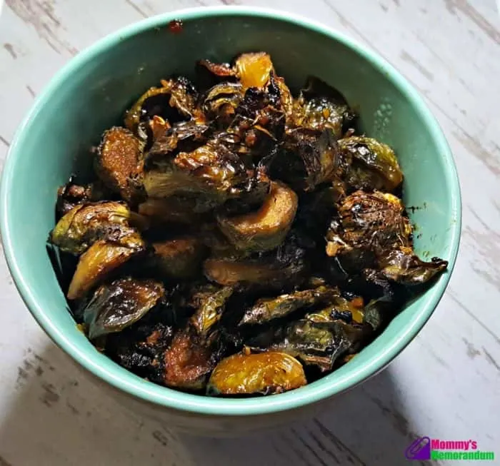 A bowl filled with crispy roasted umami Brussels sprouts, showcasing their golden and caramelized texture